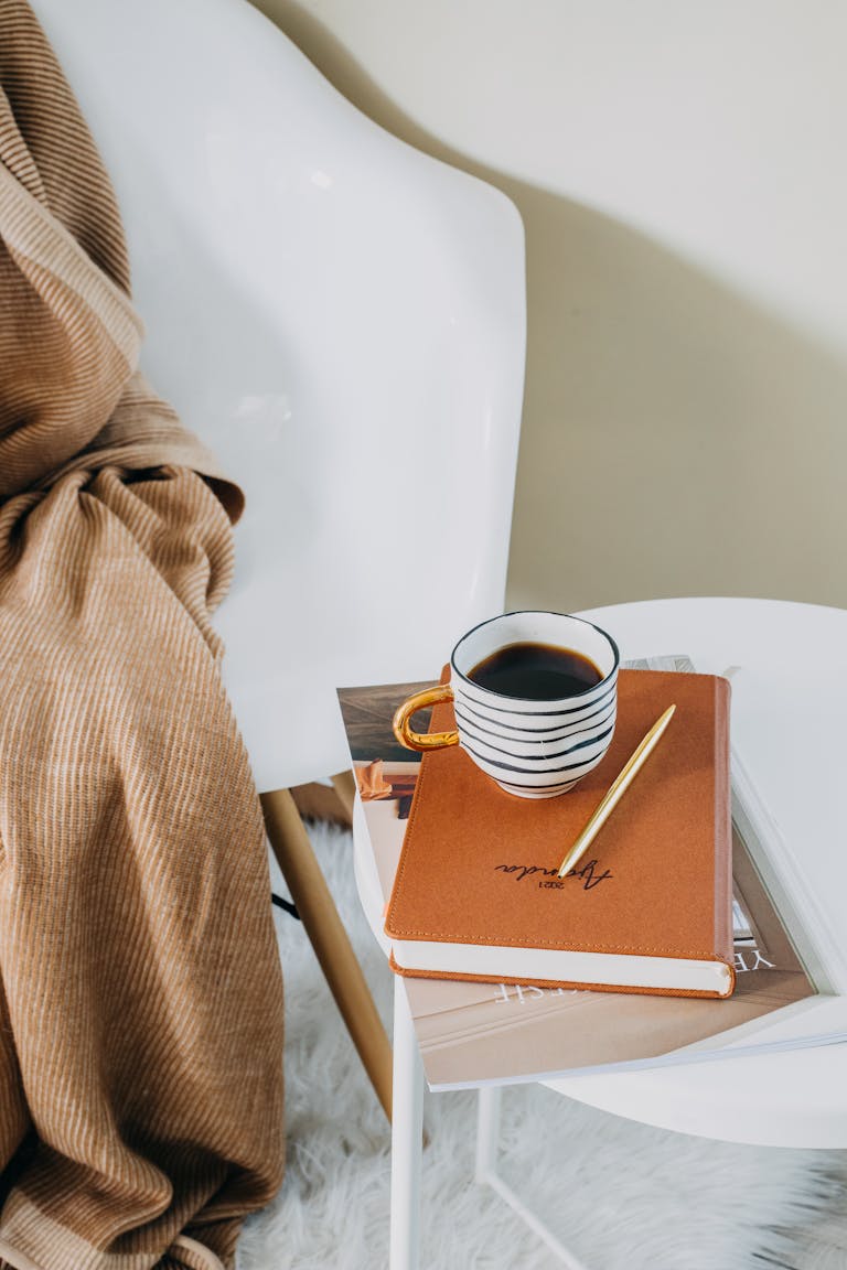 A cozy setup featuring coffee and a prayer journal on a modern chair, ideal for a relaxed morning growing your faith.
