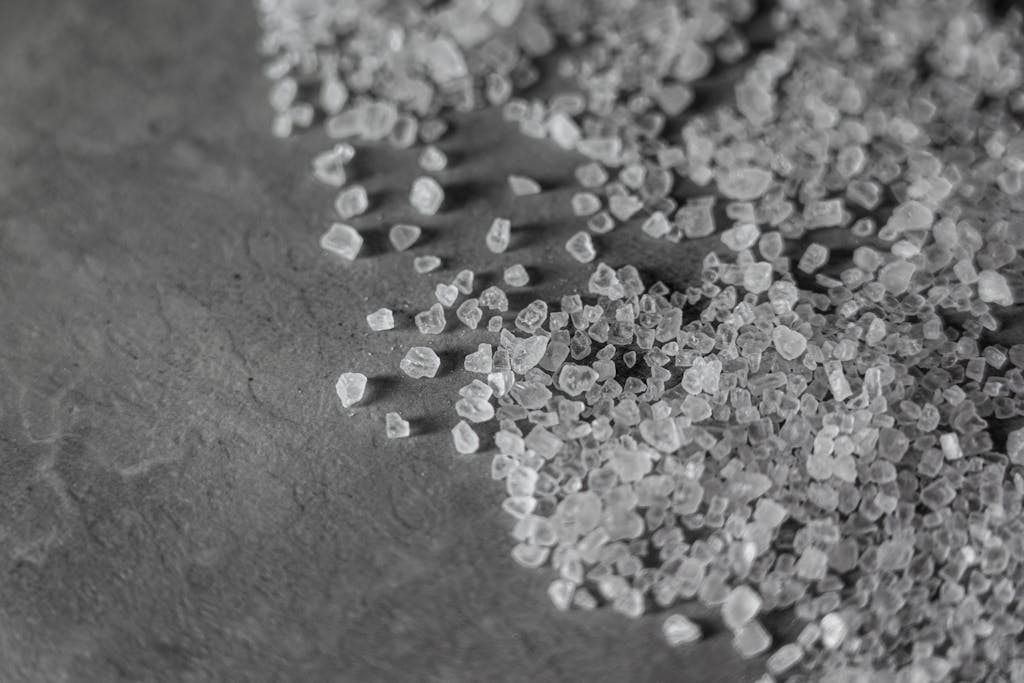 Close-up monochrome image showcasing the texture and shape of rock salt granules on a surface. Salt is used to represent the danger of looking back: a powerful lesson from Lot's wife