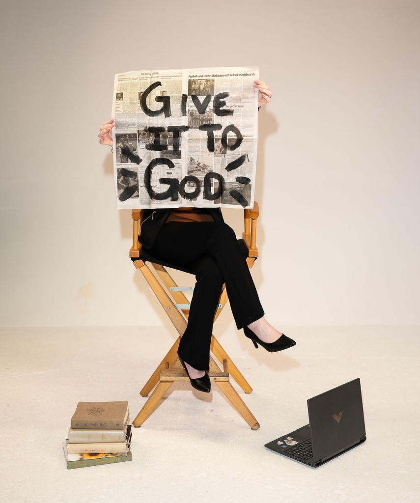 Carly holding paper that says "GIVE IT TO GOD"