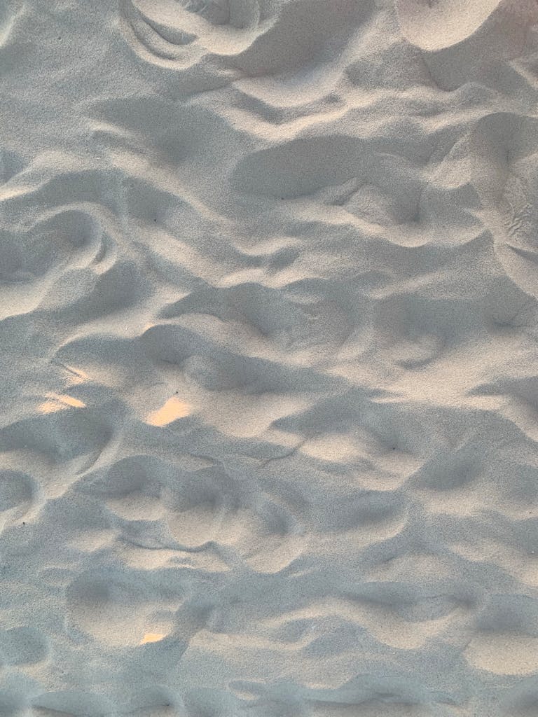 Close-up of rippling sand patterns on a beach creating a natural abstract texture.