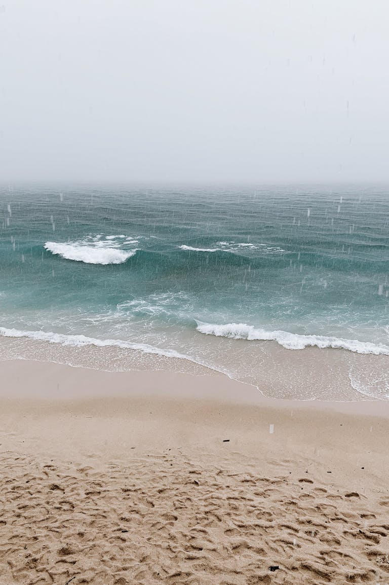 Tranquil seascape with gentle waves and raindrops on a sandy shore. Perfect for relaxation themes.