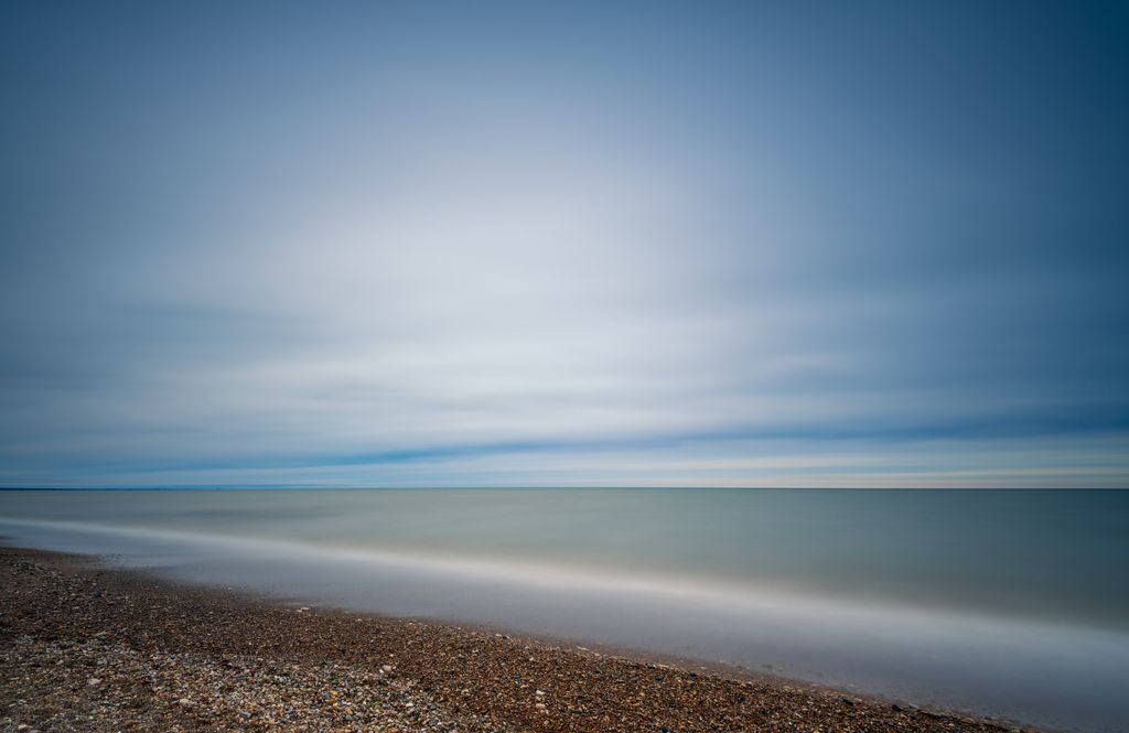 Spectacular seascape with wavy water and coast with stones under bright blue sky with clouds