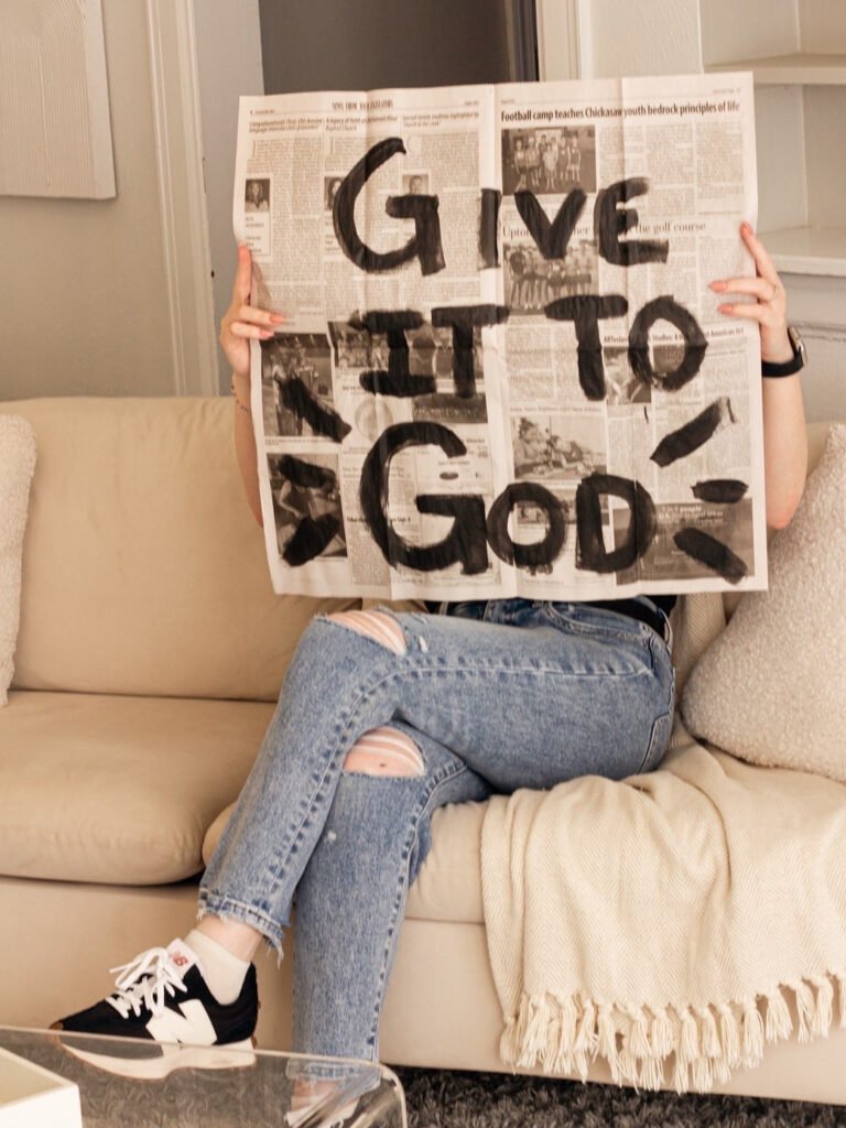 Carly, who wrote the Christian Mindset Articles for this page, holding a paper that says "GIVE IT TO GOD"