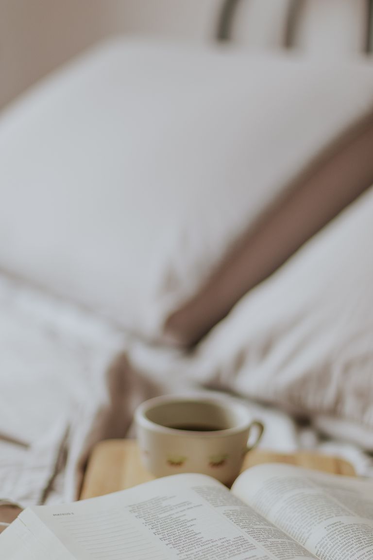 A serene morning setting on a bed with a book and coffee, perfect for relaxation.