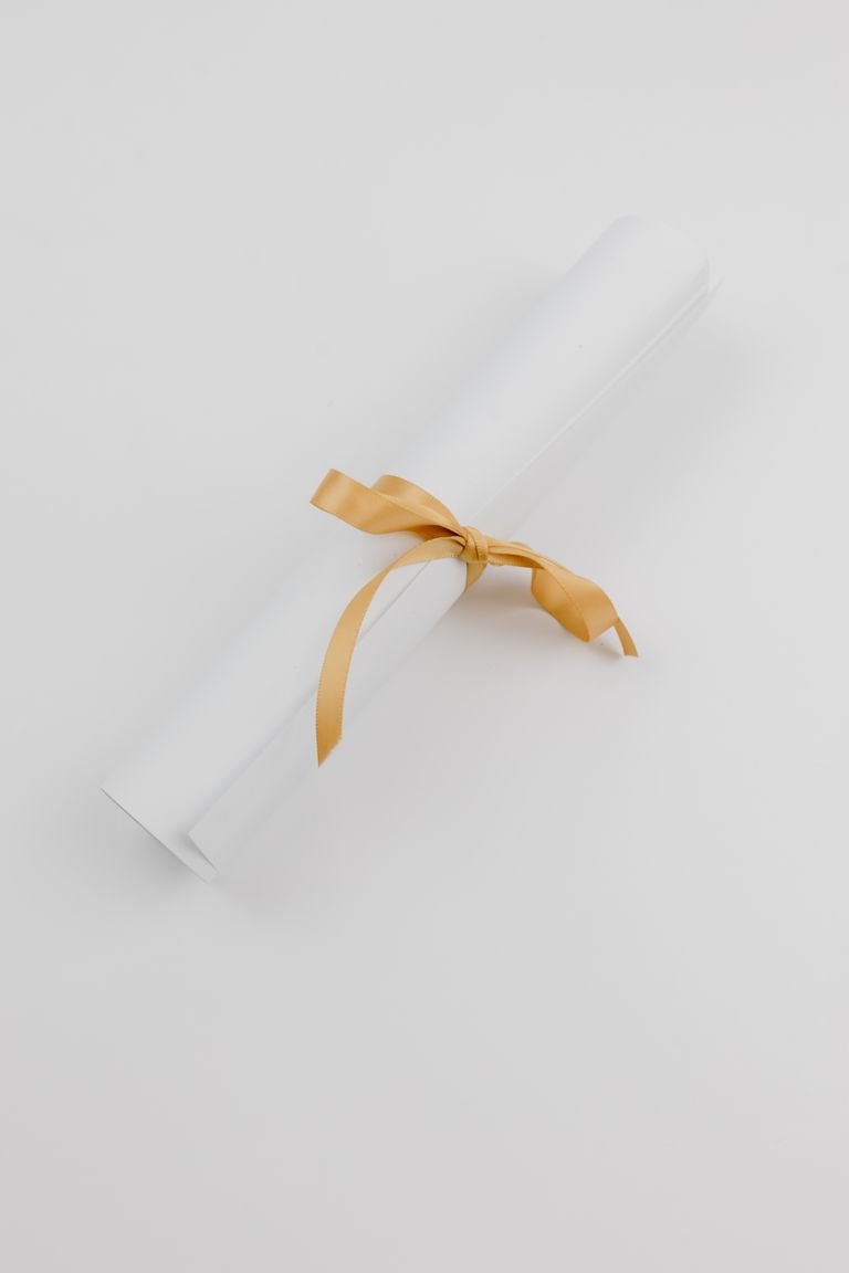 A stylish rolled paper tied with a gold ribbon, symbolizing celebration or achievement.